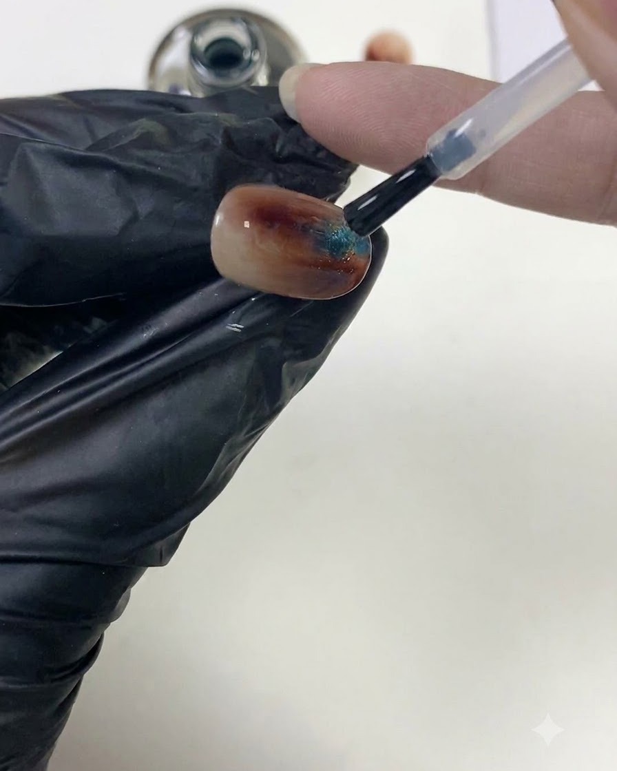 Ein Nagelpinsel glättet klaren Top-Coat über eine texturierte Bernsteinnageloberfläche, um den Apex aufzubauen.