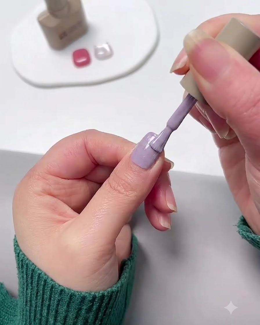 Ein Nagelpinsel trägt lila Lavendel-Gel-Nagellack auf einen Fingernagel auf.