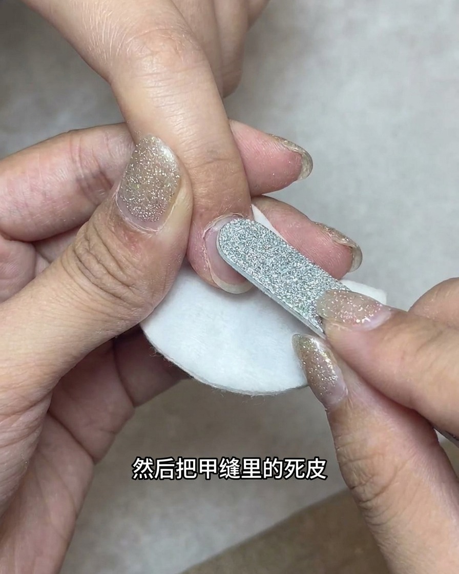 Eine Fräse mit kugelförmigem Bit zur Reinigung der seitlichen Nagelränder über einem Wattepad.