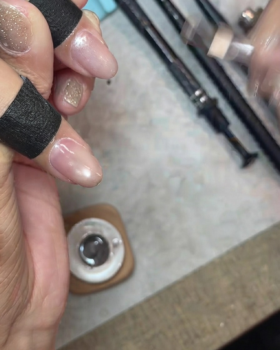 Das Auftragen einer Schicht transparenten, feinen Schimmer-Cat-Eye-Gels auf einen Fingernagel.