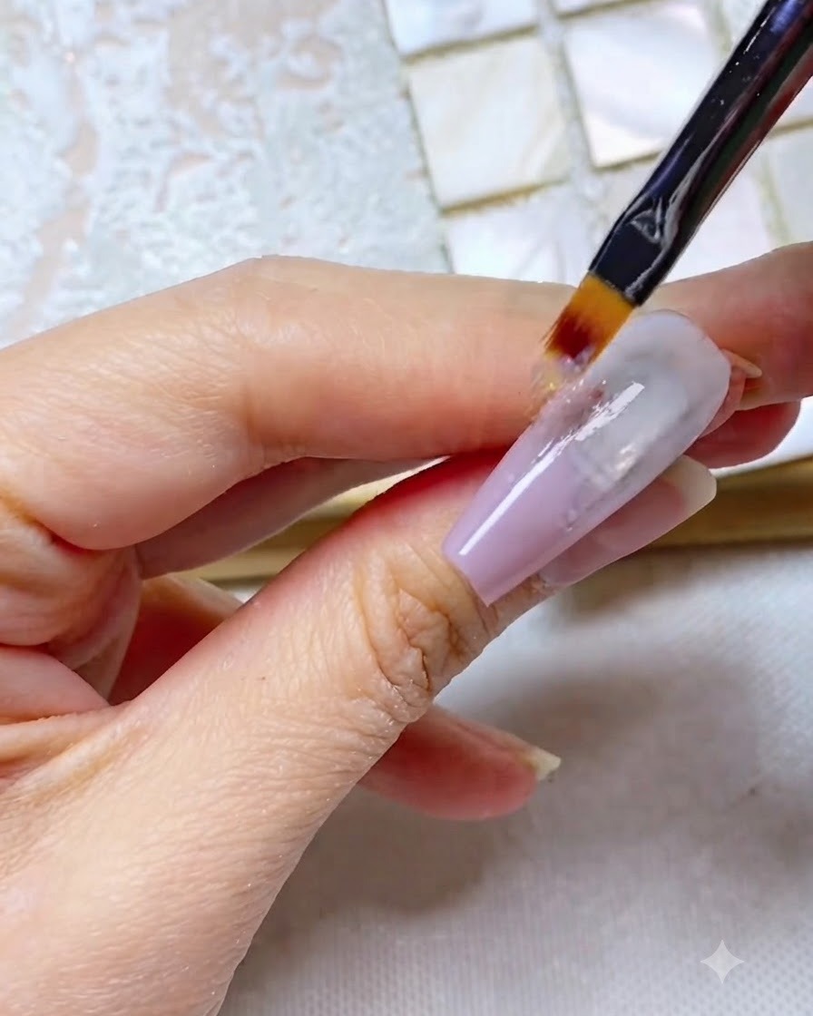 Ein Ombré-Pinsel zieht graulila Gel gerade die Nagellänge hinunter und erzeugt ein streifiges Aussehen.