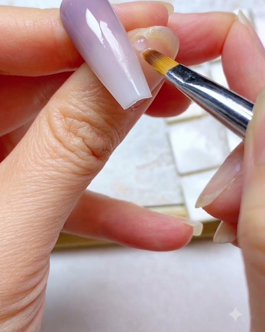 Eine Nahaufnahme eines Ombré-Pinsels, der leicht über den oberen lila Abschnitt eines Gradienten-Nagels streicht.