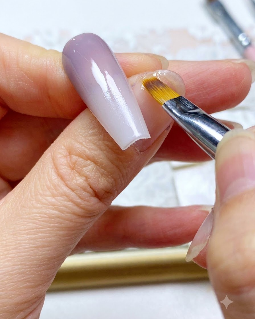 Ein Nagelpinsel führt einen letzten Retusche-Strich entlang des verblendeten Farbabschnitts des Nagels durch.