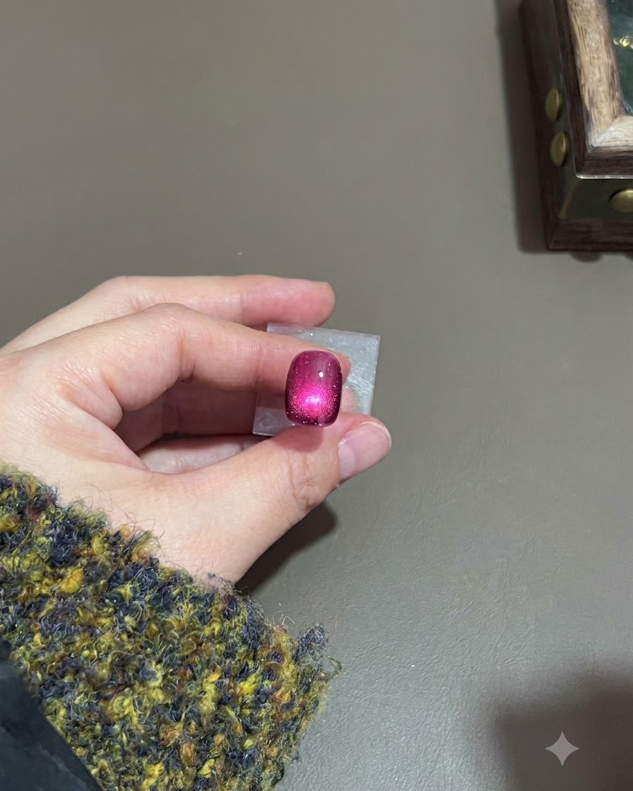 Ein dunkelvioletter Cat-Eye-Nagel mit einem ausgehärteten, leuchtenden Highlight unter einer Lampe.