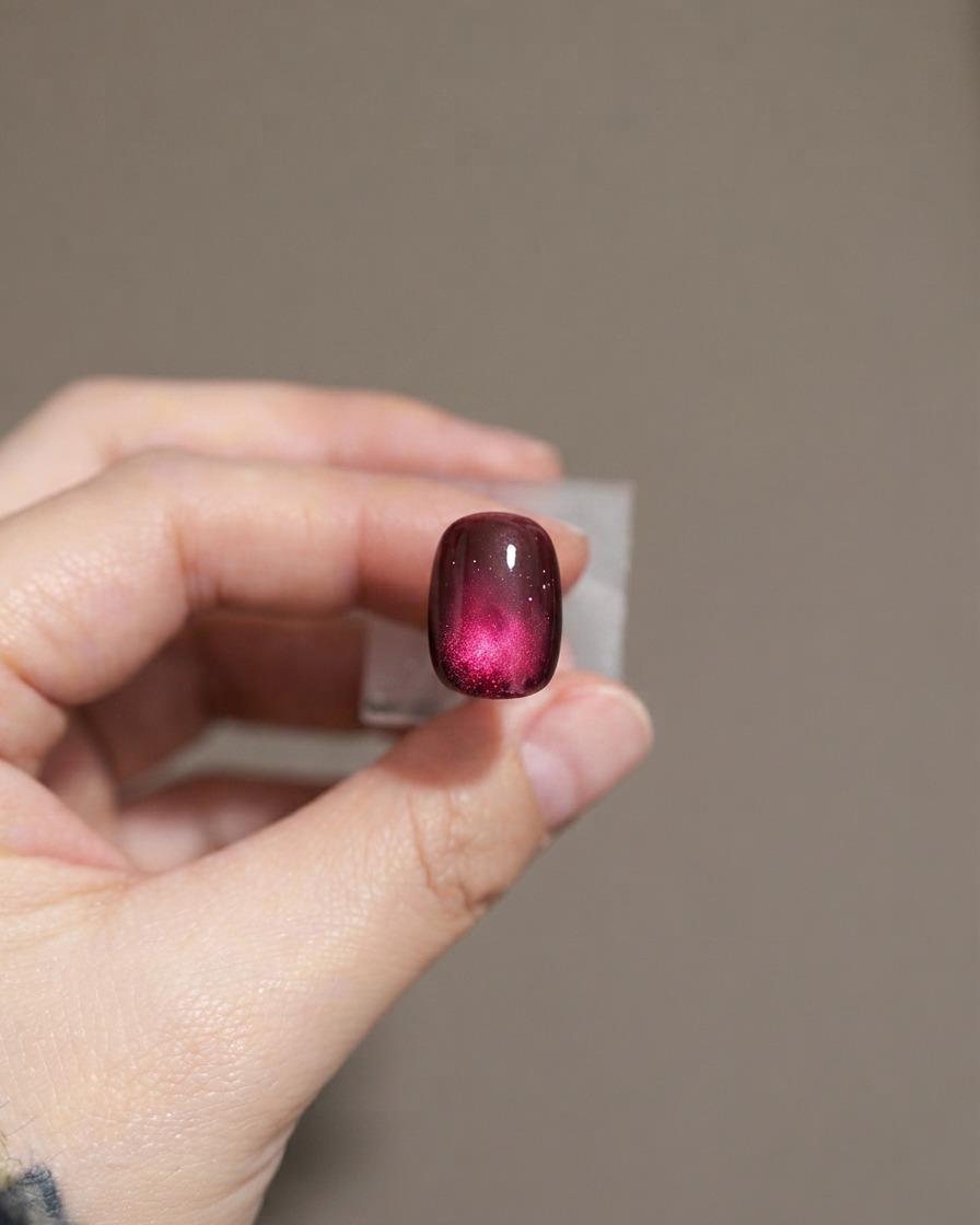 Ein Nagel zeigt eine zweite Schicht dunkelvioletten Cat-Eye-Gellacks.