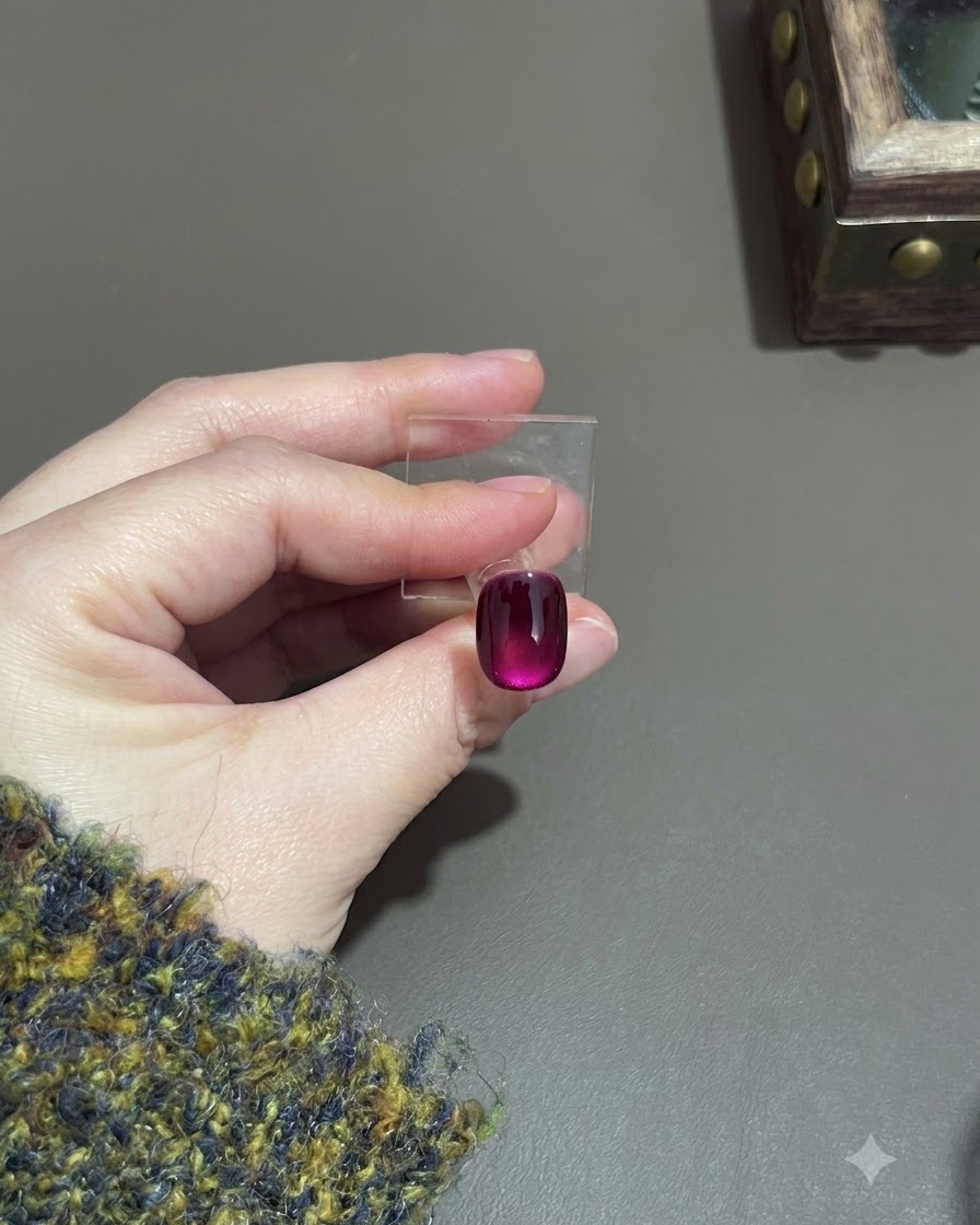 Ein ausgehärteter violetter Cat-Eye-Nagel zeigt einen tiefen Gradienteneffekt auf einem Display-Ständer.