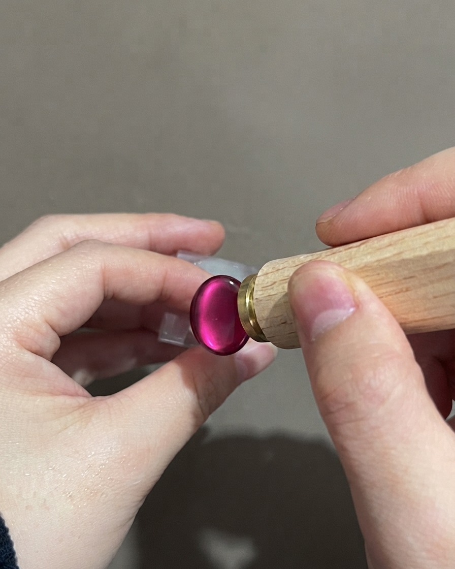 Eine Hand hält ein Nagelstempelwerkzeug in der Nähe eines fertigen violetten Gradient-Cat-Eye-Nagels.