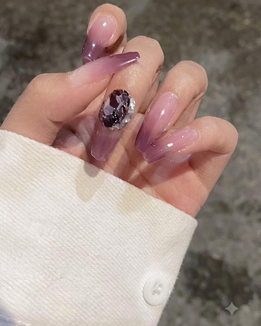 Eine Nahaufnahme eines Fingers mit einem lila Gradient-Nagel, der einen herzförmigen Kristall zum Vergleich zeigt.
