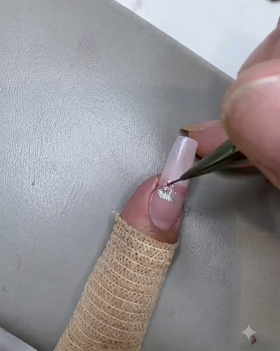 Ein feiner Liner-Pinsel trägt einen zweiten rosa Cat-Eye-Gelstreifen unterhalb des Silberstreifens auf den Nagel auf.