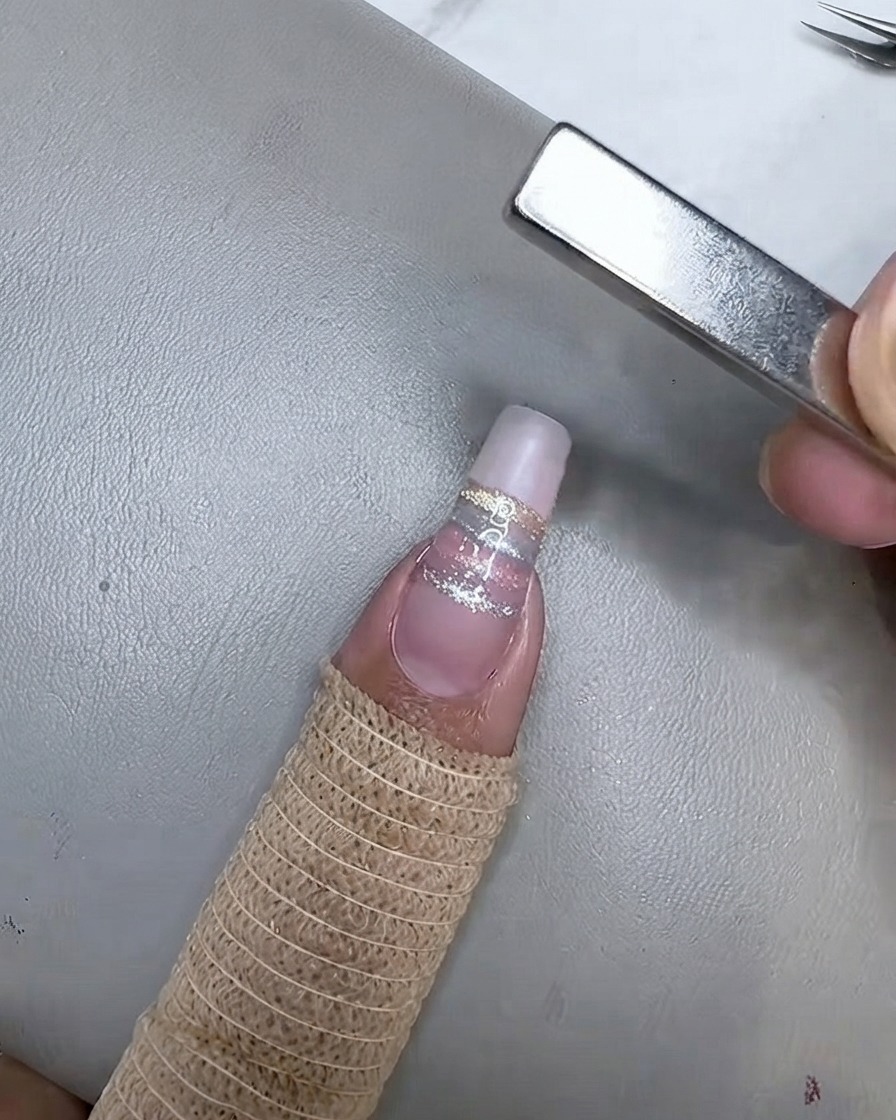 Der Nagel härtet unter einer Mini-UV/LED-Lampe aus, nachdem der champagnerfarbene Cat-Eye-Streifen magnetisiert wurde.