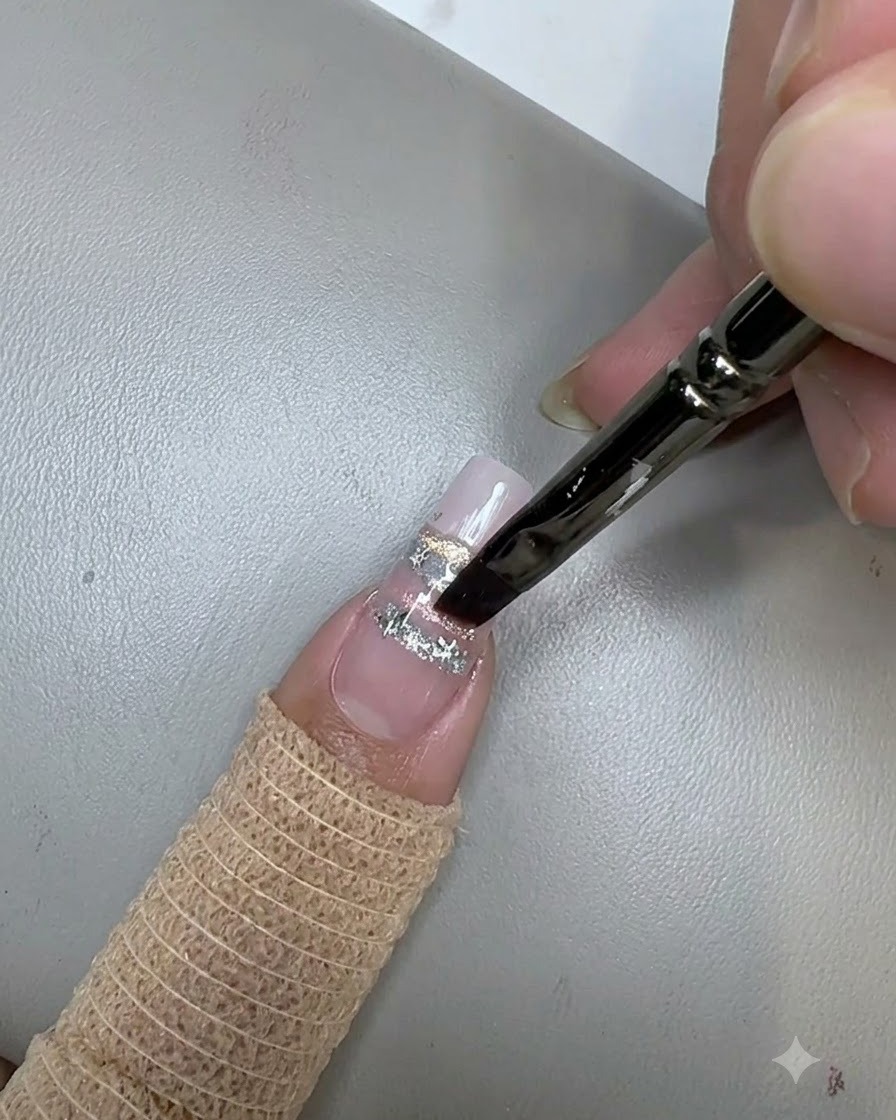 Ein Nagelpinsel trägt einen klaren Top-Coat über Stern-Pailletten auf einem verzierten Nagel auf.