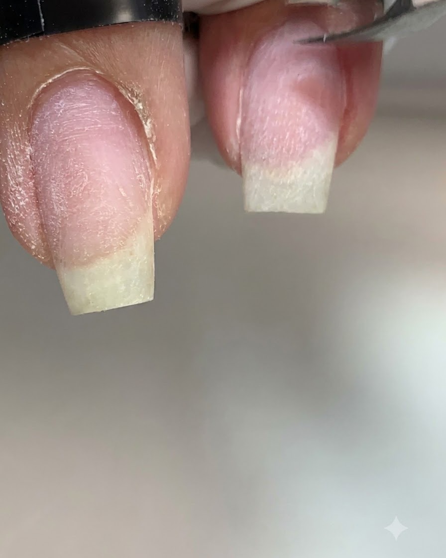 Extreme Nahaufnahme einer Nagelhautzange, die trockene Haut an der linken Seitenlinie eines Naturnagels präzise abschneidet.