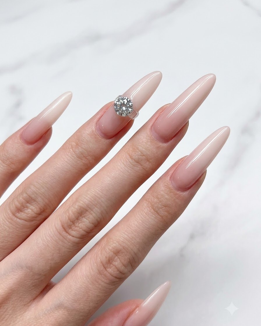 Ein Nagelpinsel trägt eine dünne Schicht durchscheinenden Nude-Unterlack auf einen langen Stiletto-Nagel auf.