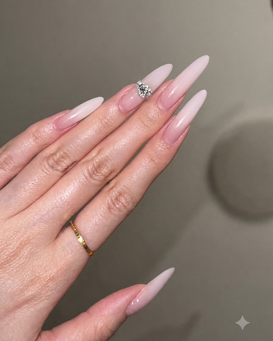 Eine Nahaufnahme zeigt das Auftragen einer zweiten Schicht milchweißen Gels zur Verstärkung der Opazität an der Nagelspitze.