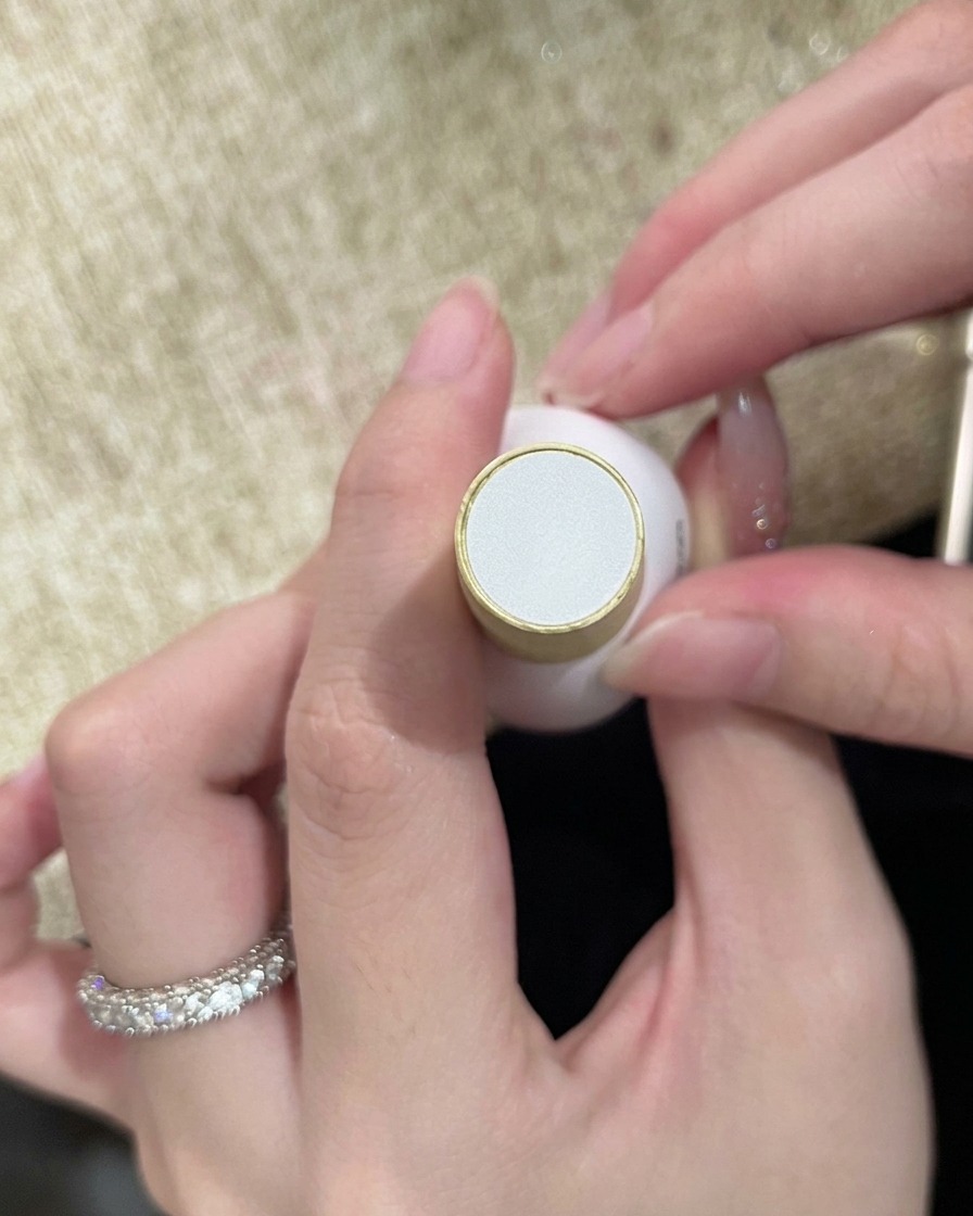 Eine Flasche Klarlack wird in der Hand gehalten, bereit, das fertige Nageldesign zu versiegeln.