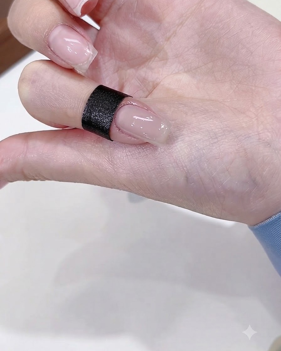 Eine Nahaufnahme eines Fingernagels, der mit einem glänzenden, nudefarbenen Basis-Gel lackiert ist.