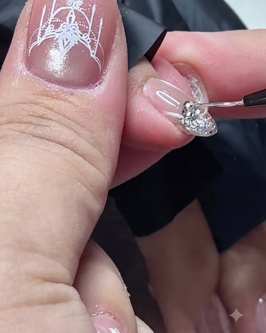 Ein feiner Detailpinsel trägt Top Coat um die Basis eines Strasssteins auf einem Nagel auf.