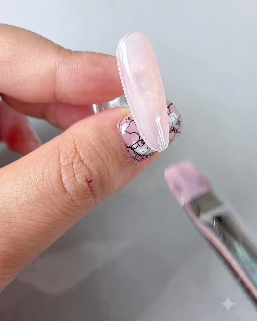 Ein Schwammapplikator, der Goldpuder auf ein ausgehärtetes florales Nageldesign reibt.