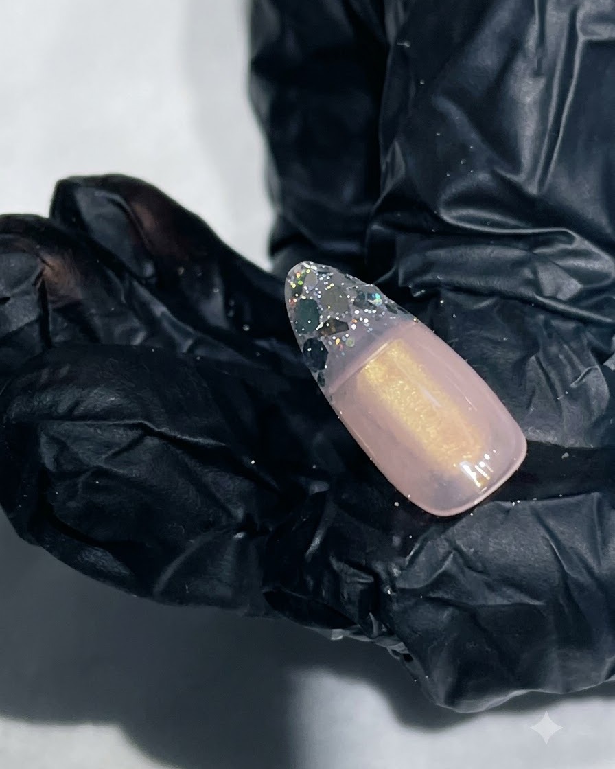 Nahaufnahme eines Nagels mit glattem Verstärkungsgel, das die Glitterspitze verkapselt.