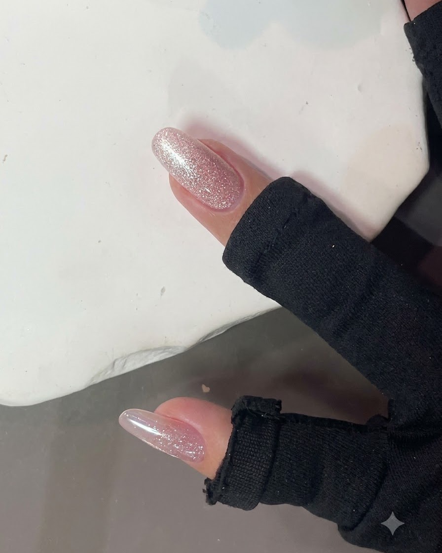 Ein starker Nagelmagnet wird nah an einen glänzenden rosa Glitzernagel gehalten, um einen Cat-Eye-Lichteffekt zu erzeugen.
