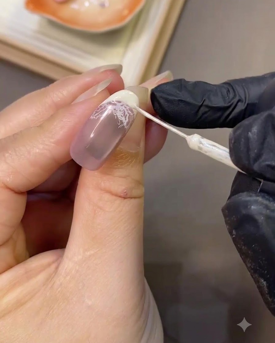 Ein feiner Liner-Pinsel verfeinert präzise die weiße Kurve einer French-Spitze auf einem manikürten Nagel.