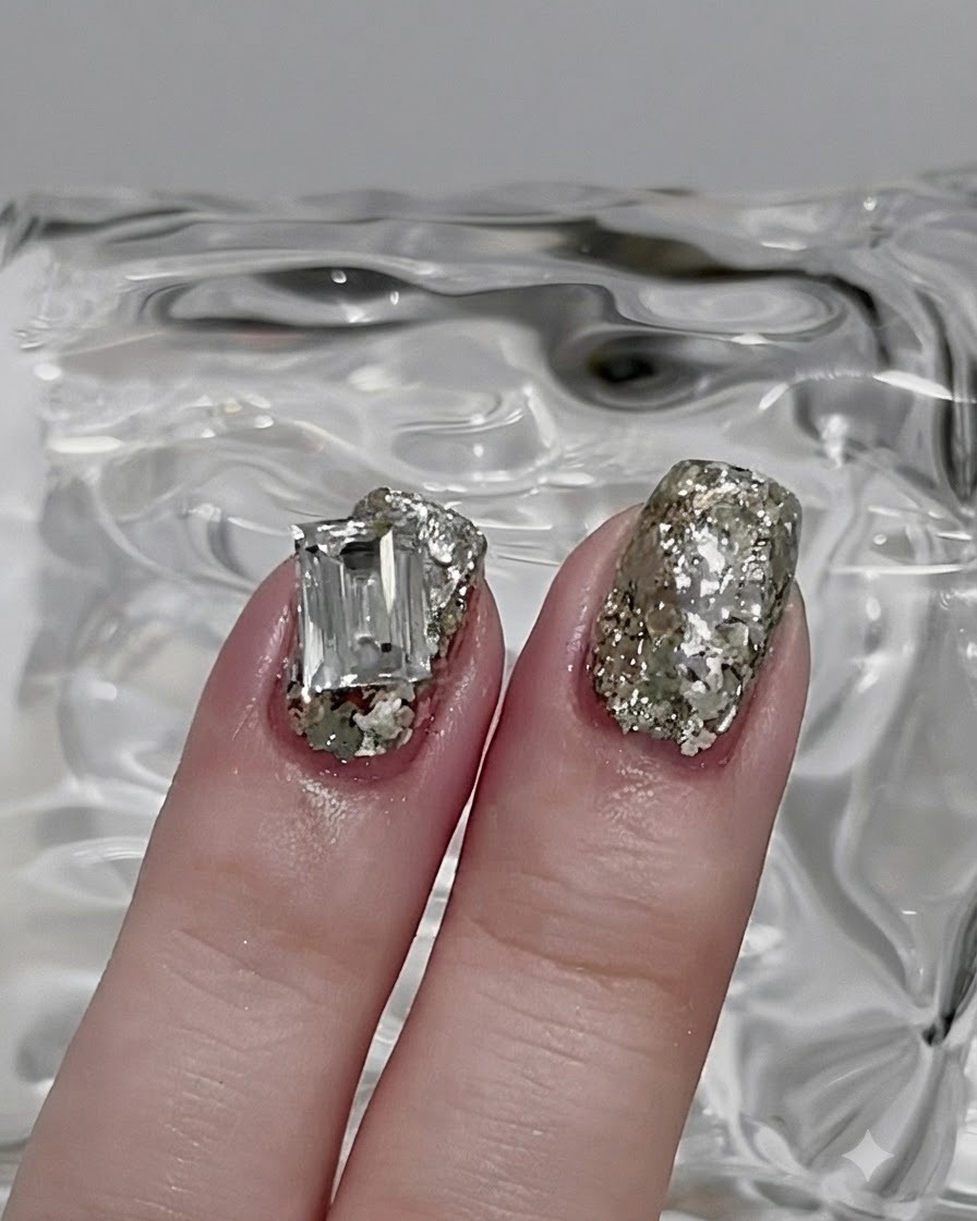 Ein Nagelpinsel glättet den Silberglitzer zu einer dünnen, gleichmäßigen Schicht auf dem Nagel.