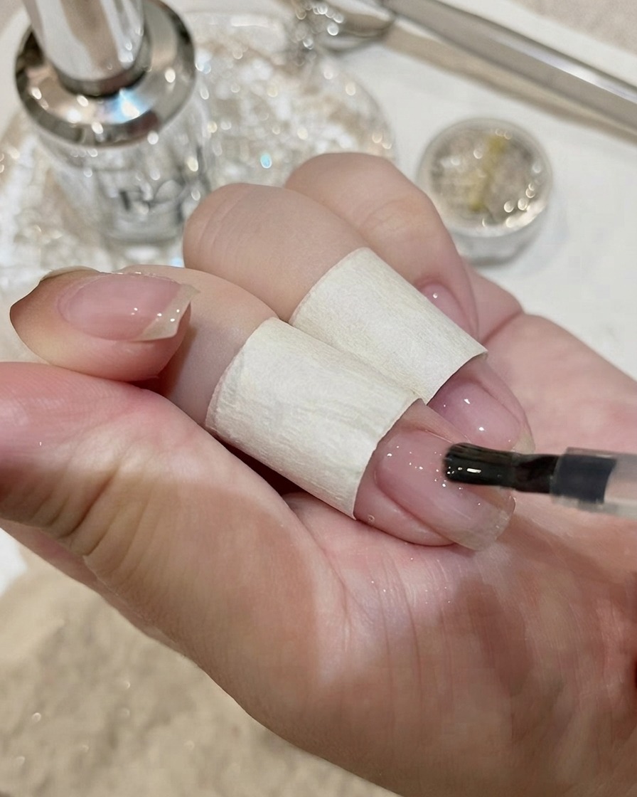 Eine Nahaufnahme des Platzierens eines großen, rechteckigen Kristalls auf einem Nagel mit Kleber.