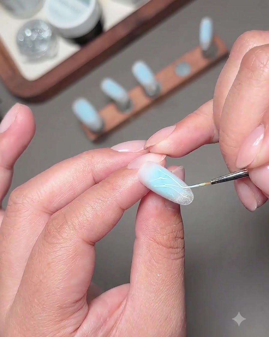 Ein feiner Pinsel trägt glitzernde Fragment-Diamant-Gel-Linien auf den verzierten Nagel auf.