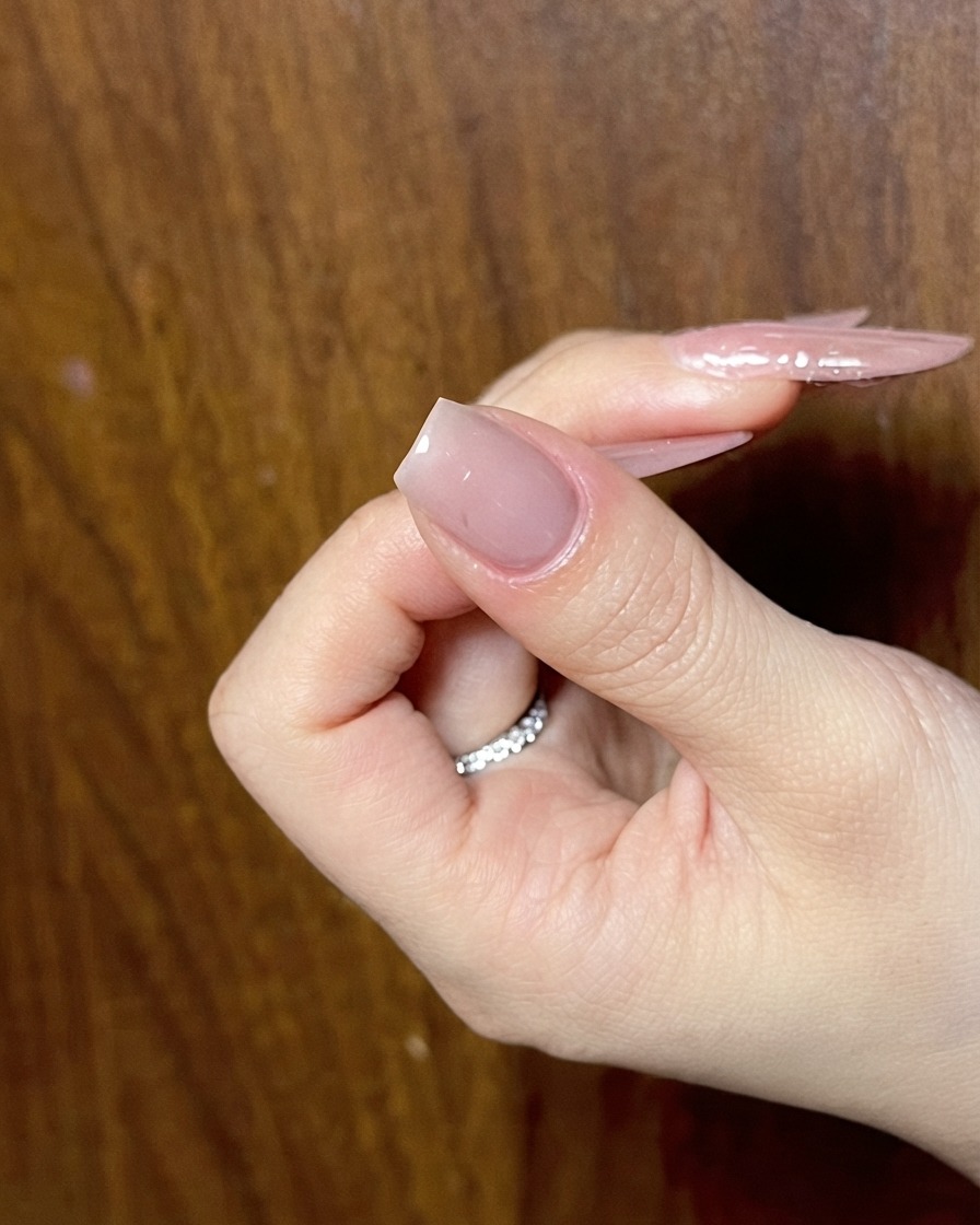 Eine Hand zeigt einen vorbereiteten Nude-Nagel, bereit für die nächste Phase des detailreichen Nail Art.