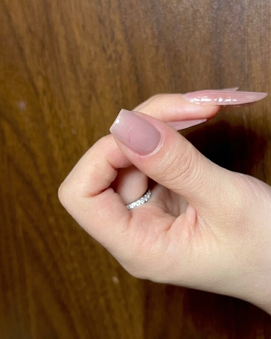 Nahaufnahme von schwarzem Gel, das verwendet wird, um die Flügelformen eines Schleifendesigns auf einem Fingernagel nachzuziehen.