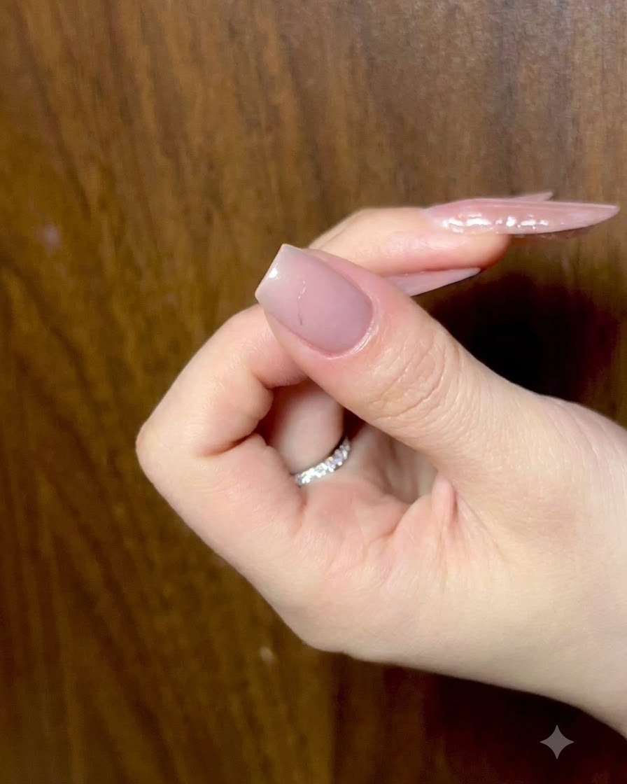 Eine Hand ruht mit leicht gekrümmten Fingern und zeigt vorbereitete Nude-Nägel unter Umgebungslicht.