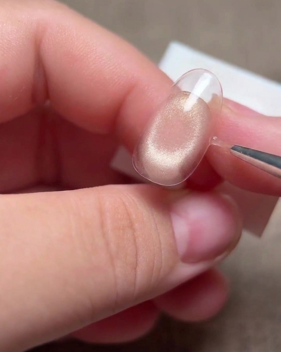 Eine Hand verwendet einen dünnen Liner-Pinsel, um die Kanten der Smile-Line auf einer Nagelspitze zu verfeinern.