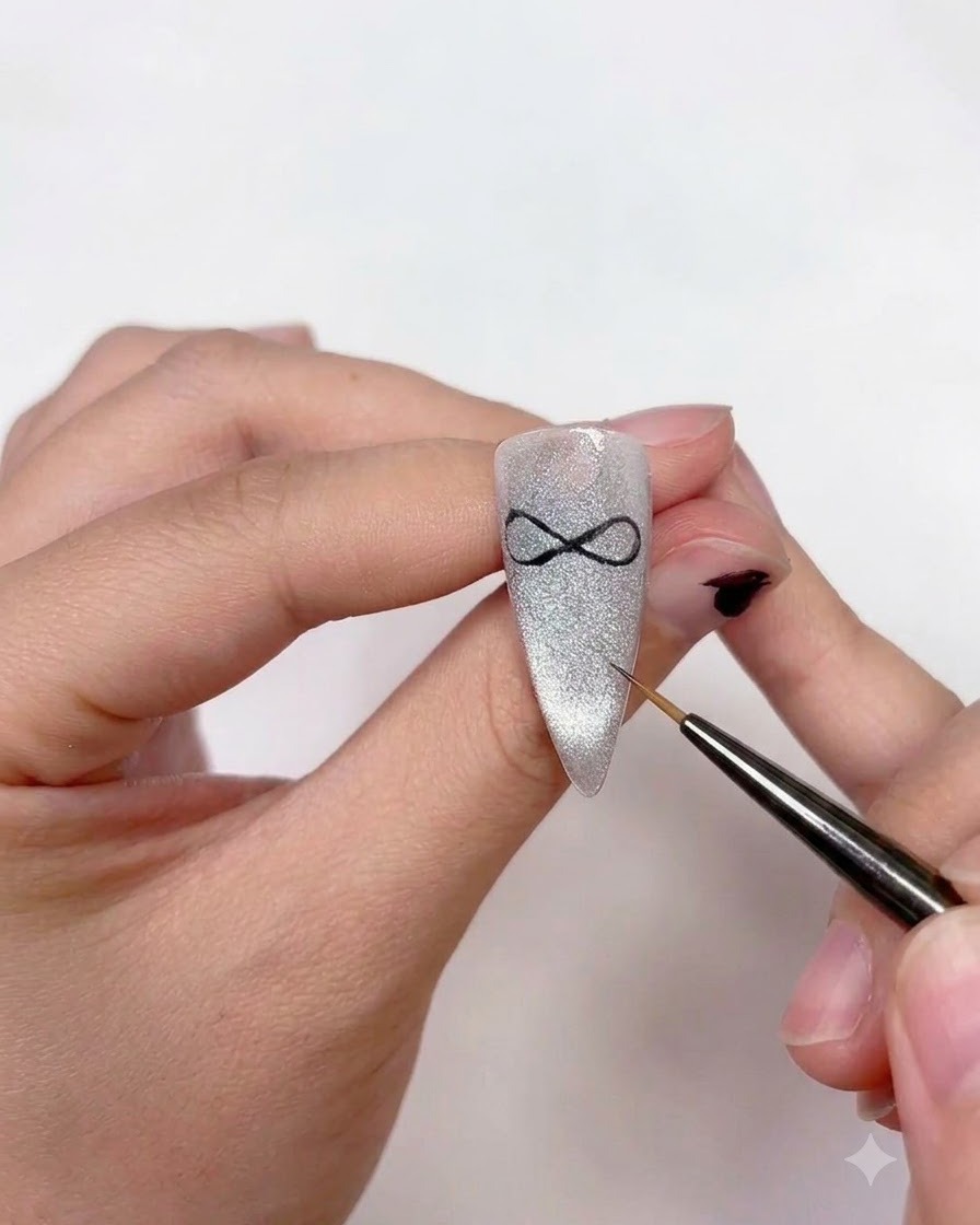 Eine Nageldesignerin verwendet einen feinen Liner-Pinsel, um zwei geschwungene Bandenden hinzuzufügen, die von der Mitte der Schleifenkunst nach unten verlaufen.