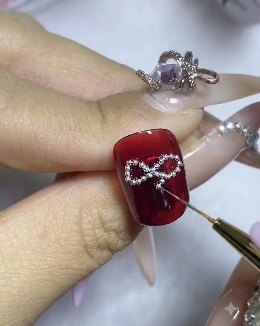 Eine Nahaufnahme eines Nagels mit einem zentralen Strassstein, der in der Mitte des Perlen-Schleifen-Gerüsts angepasst wird.
