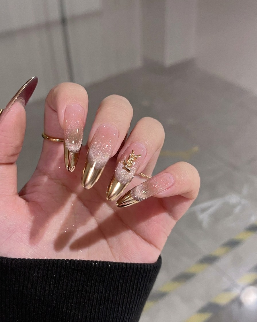Eine geneigte Hand zeigt die glänzende Nude-Gelbasis und das goldene YSL-Charm.