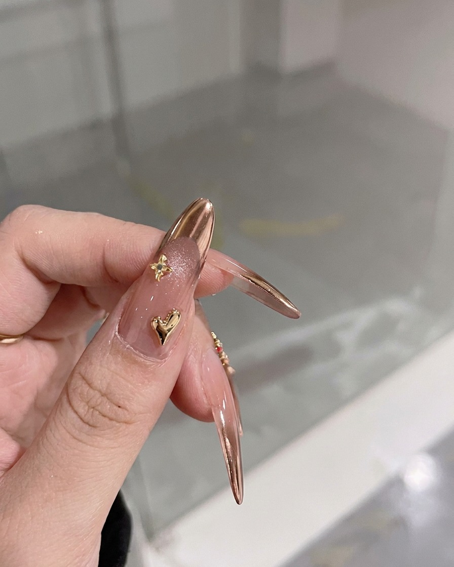 Eine Nahaufnahme eines Fingers mit einem winzigen 3D-Goldherz-Charm nahe der Nagelhaut.