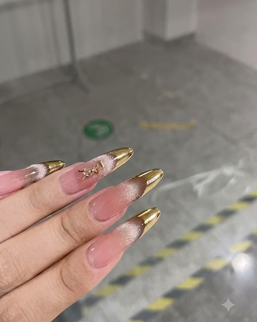 Eine Handdrehung im Nahbereich zeigt fertige mandelförmige Nägel mit Bronze-French-Spitzen.
