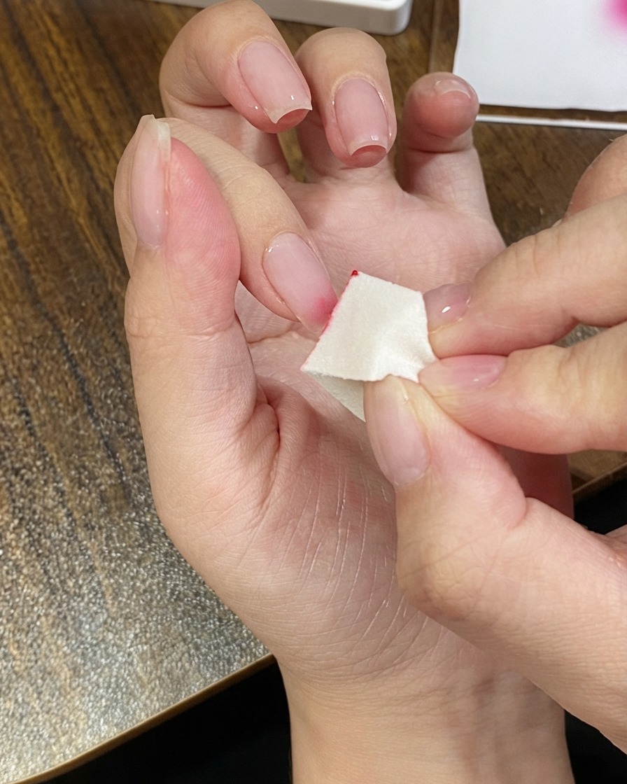 Eine Hand hält einen kleinen Schwamm-Applikator, um rosa Gel auf eine Nagelspitze aufzutragen.