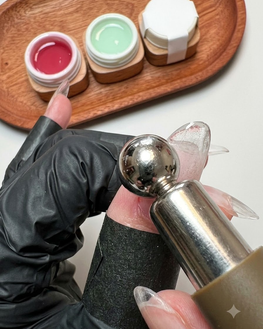 Ein Magnetstab schwebt nah über einer nassen Glitter-Gel-Nageloberfläche.