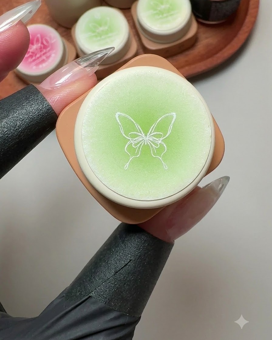 Ein Solid-Gel-Behälter mit einer Schmetterlingsillustration auf dem Deckel, umgeben von grünen und rosa Gel-Töpfen.