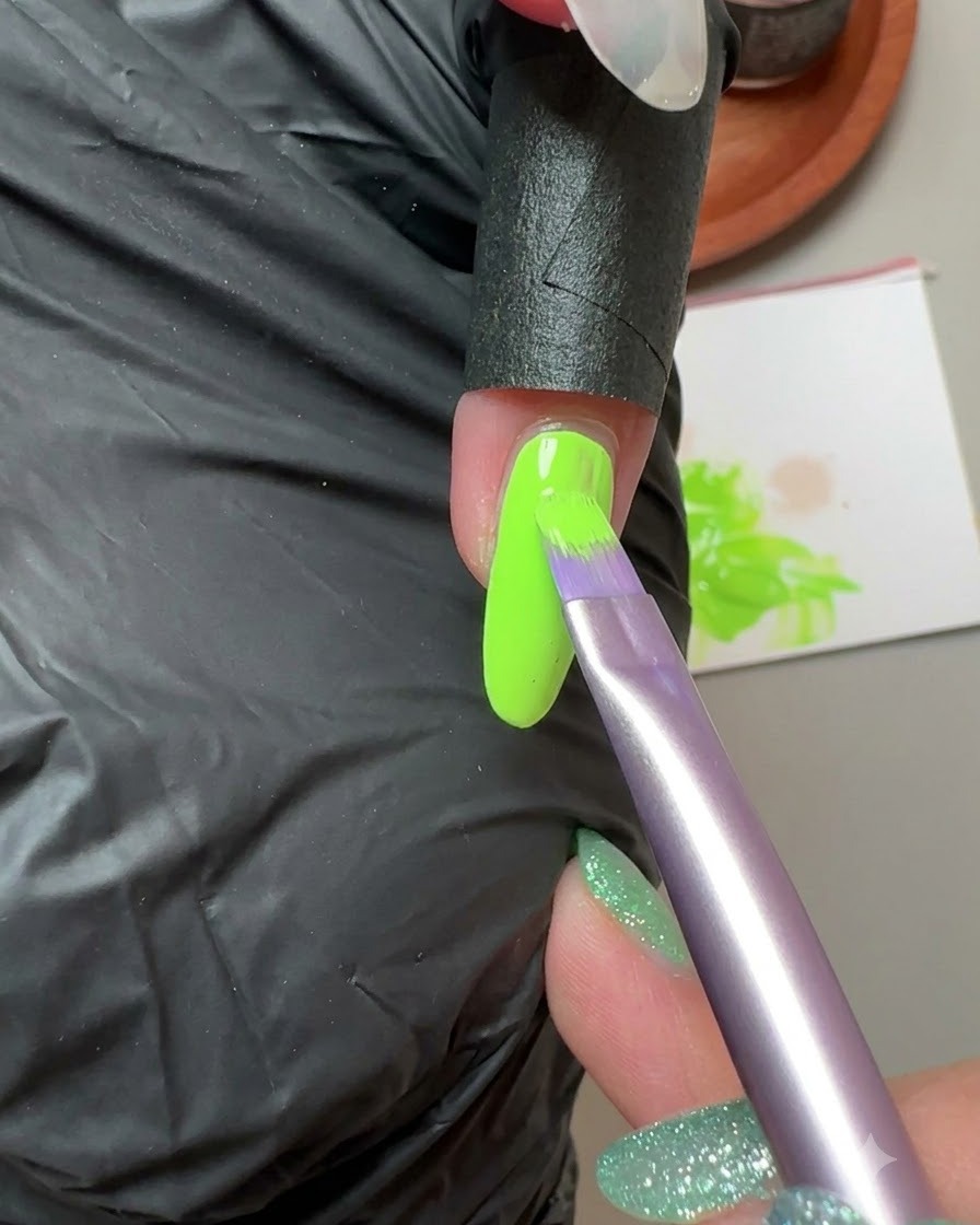 Ein Pinsel trägt fluoreszierendes grünes Solid Gel auf den kleinen Fingernagel auf.