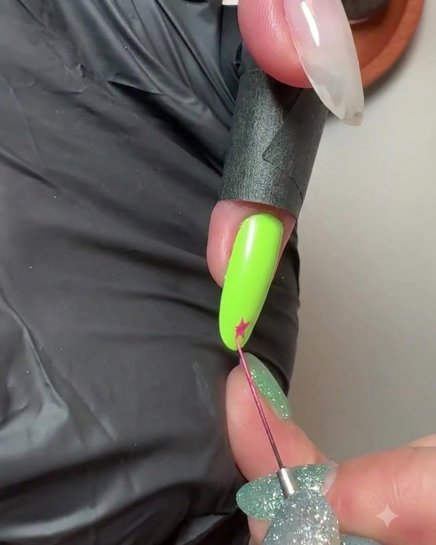 Ein feiner Liner-Pinsel zeichnet einen kleinen rosa Stern auf die Spitze eines neongrünen manikürten Nagels.