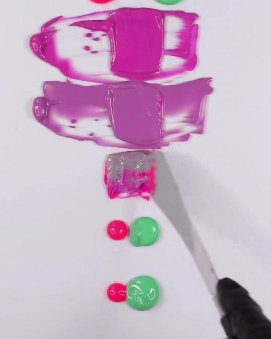 Ein Metallspatel mischt eine Kombination aus rosa und grünem Gel-Polish, um einen gedämpften lila Ton zu erzeugen.