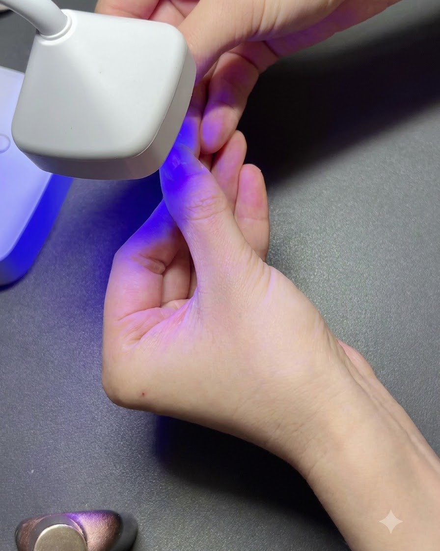 Eine tragbare weiße UV-Lampe härtet einen klaren Gel-Nageltip auf einem Finger unter violettem Licht aus.