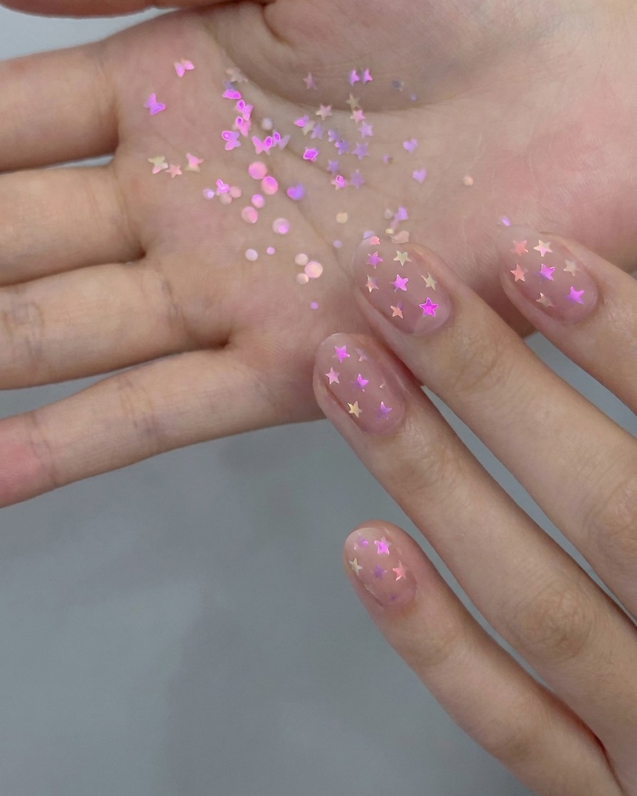 Ein Manikürepinsel trägt eine dünne Schicht transparenten Nude-Gel-Lacks auf einen natürlichen Fingernagel auf.