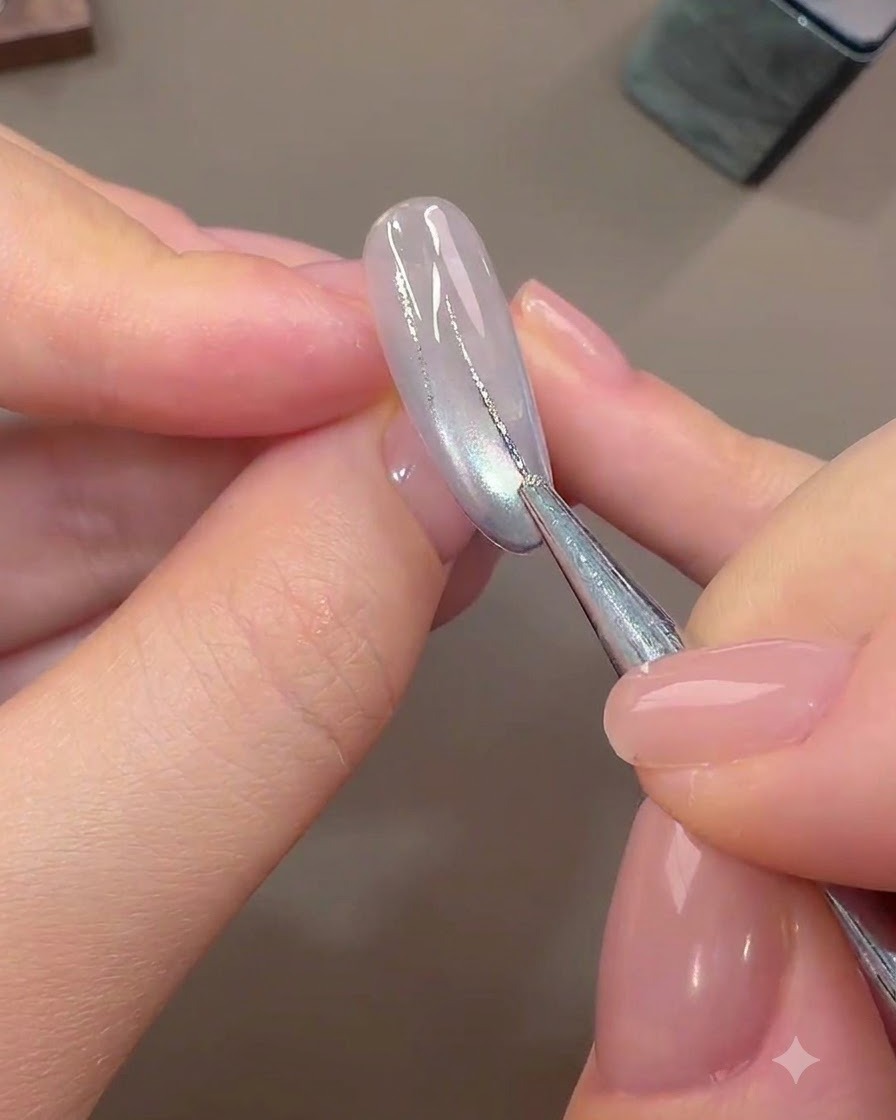 Ein feiner Nail-Art-Pinsel zeichnet dünne abstrakte Linien mit Silberfolien-Gel über einen hellfarbigen, ausgehärteten Basisnagel.