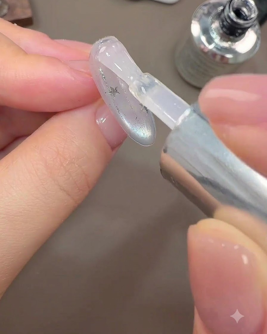 Ein Pinsel trägt eine abschließende glänzende Top-Coat-Schicht auf ein Galaxie-Nageldesign auf.