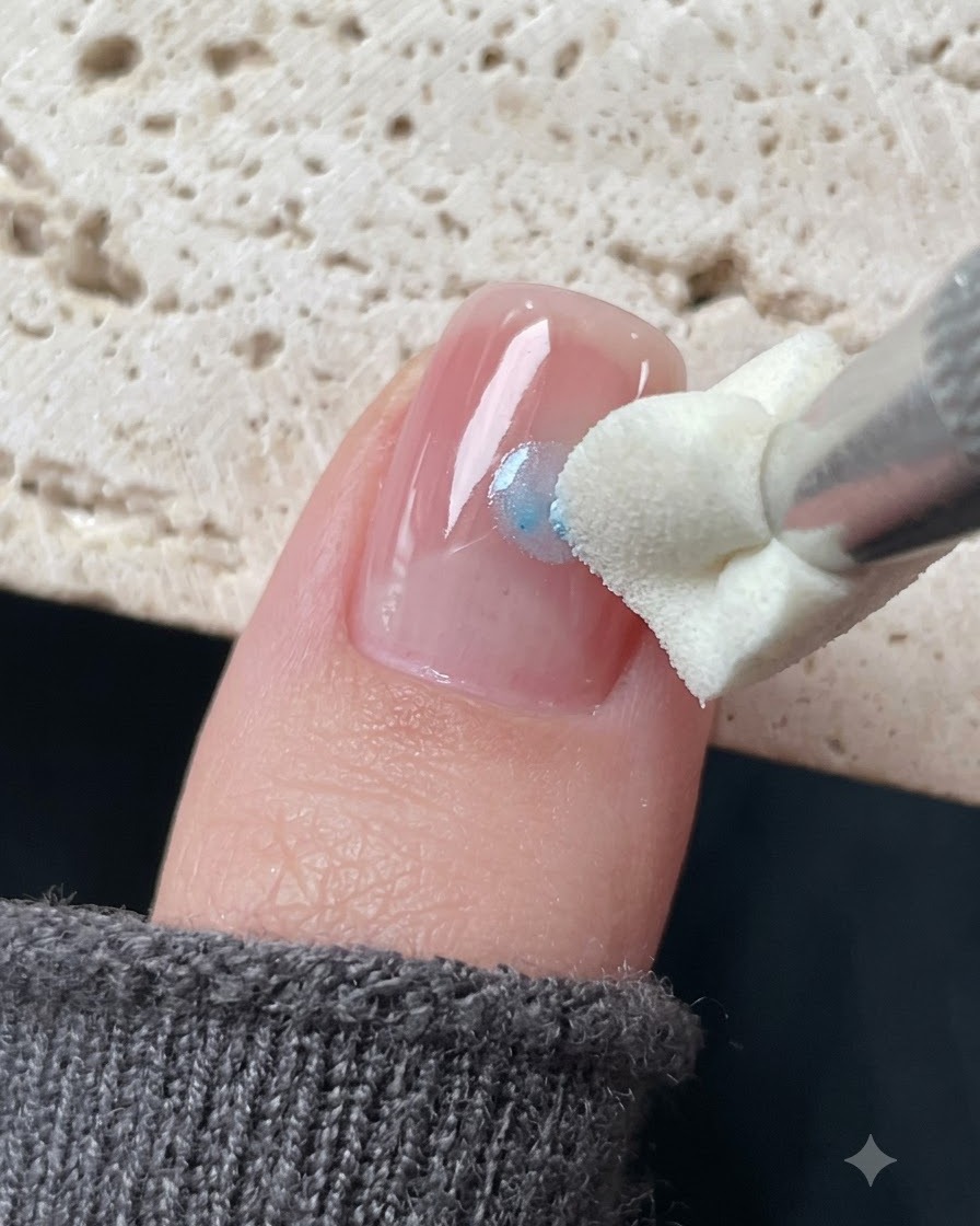 Ein Silikon-Stempelwerkzeug tupft blaues Glasgel um einen Sternaufkleber auf einem Nagel.