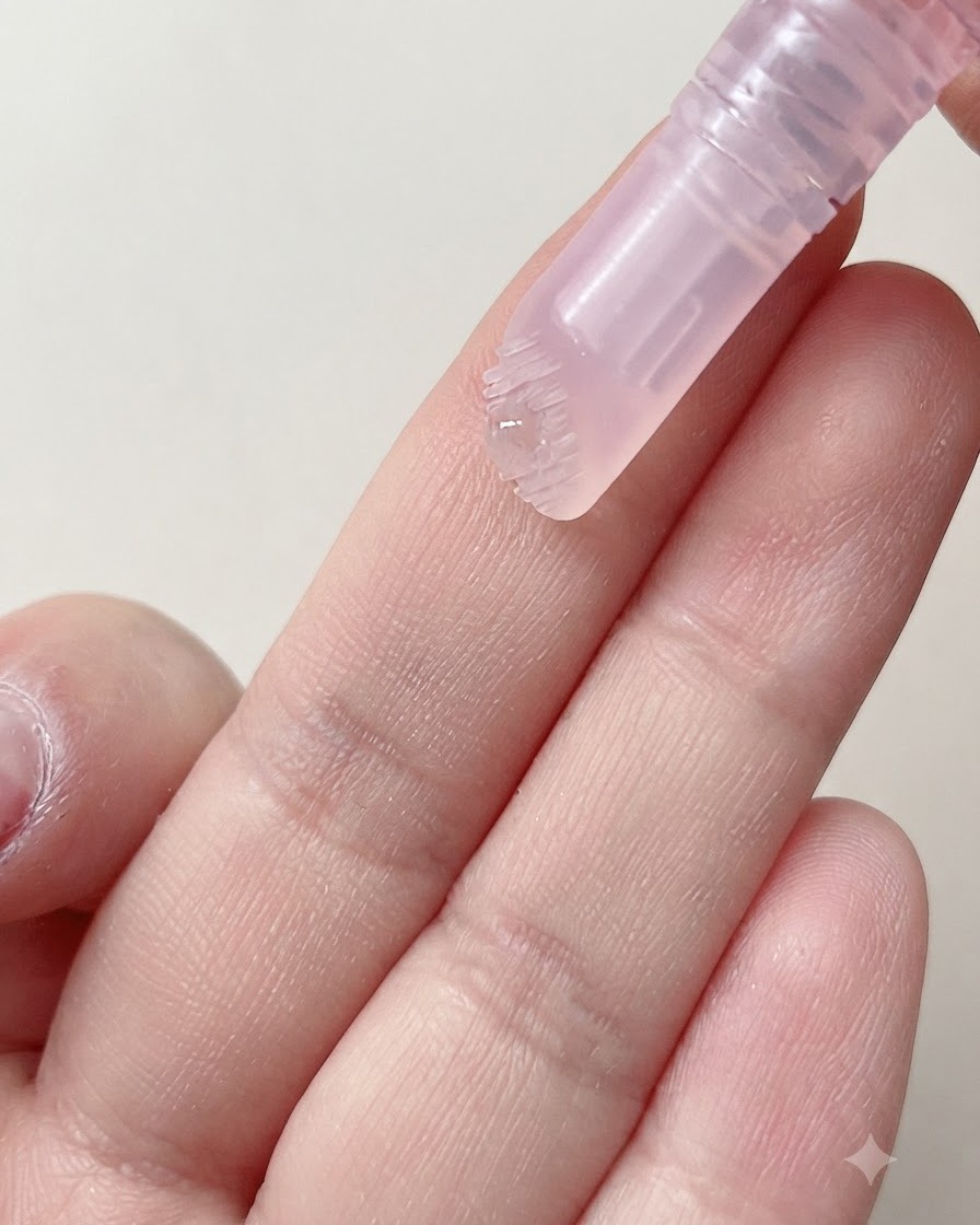Ein weicher Pinselkopf eines Nagelstifts gibt einen Tropfen feuchtigkeitsspendendes Serum auf einen Finger ab.