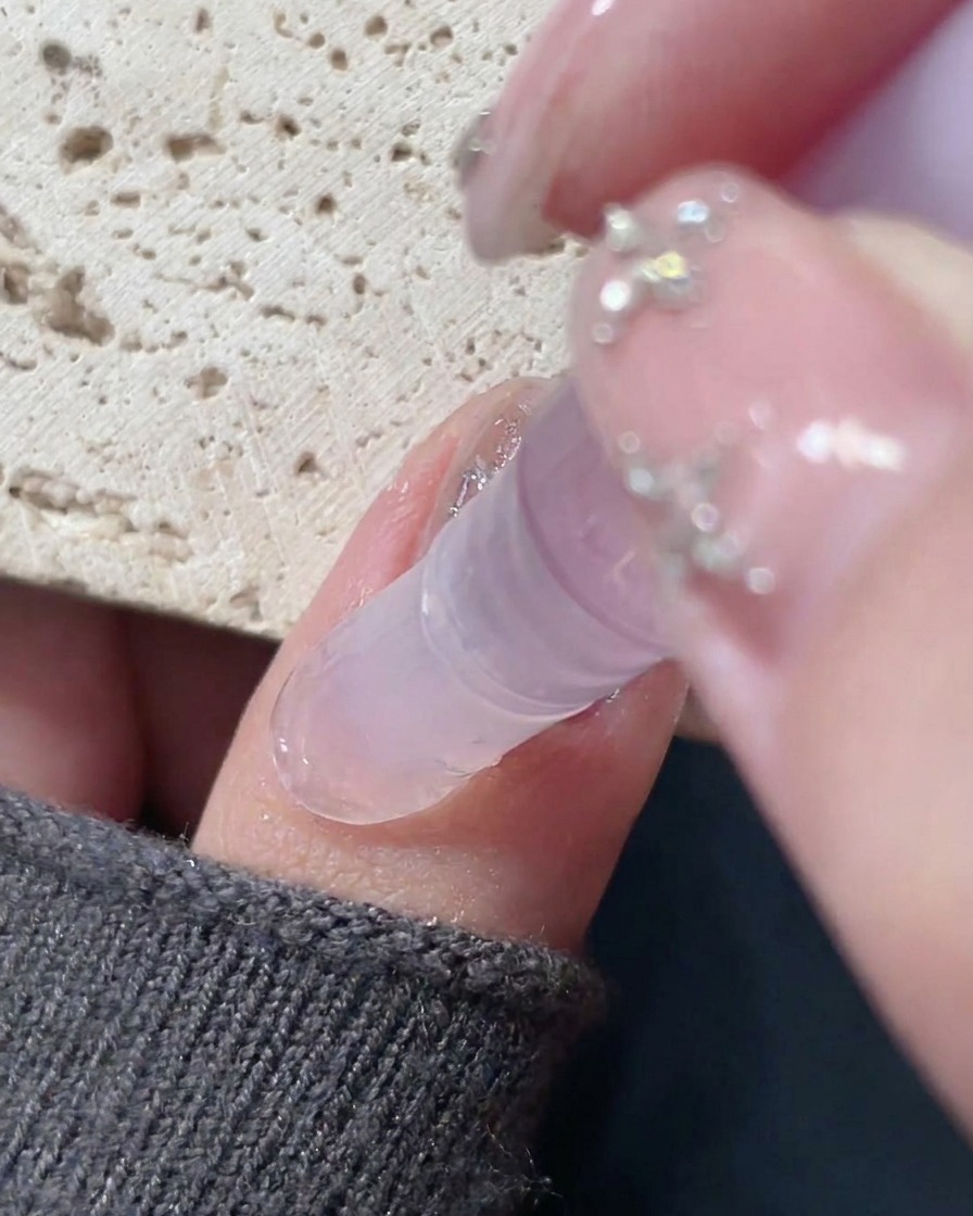 Ein Nagelölstift wird um den Rand eines fertigen Nagels aufgetragen, um die Haut mit Feuchtigkeit zu versorgen.